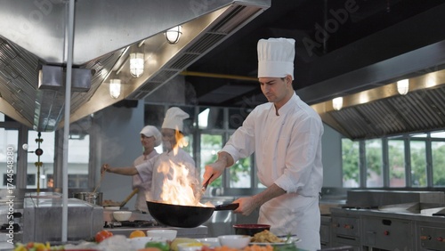 Male chefs cook over fire in pan, chef preparing food in restaurant