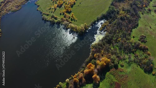 An aerial shot of the Shihan Juraktau mountain and surrounding landscape in the South Ural region of Russia during the autumn season. The footage captures the vibrant fall foliage, a calm body of wate