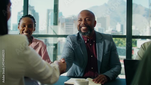 Confident business colleagues shaking hands while discussing in boardroom during daytime
