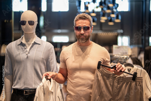 Mature man choosing shirt and trousers. Designer clothing in luxury store. Luxury shopping for a stylish man. Male fashion shop. Stylish man in menswear boutique