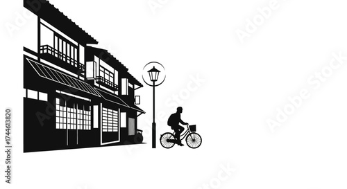 A silhouette of a person riding a bicycle past traditional Japanese buildings and a street lamp.