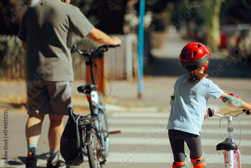 Dad and his Daughter Crossing the Street Alongside their Bikes. Father teaching his little kid bicycle traffic rules 
