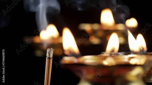 Naraka Chaturdashi : Hypnotic Wisps of Smoke Rising from Smoldering Incense Sticks with Glowing Candles in the Background