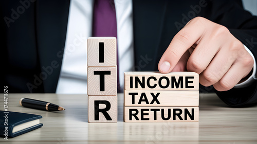 Itr and income tax return blocks with hand and pen on desk