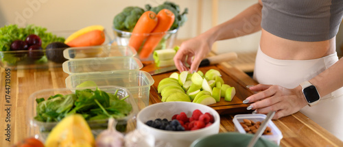 Fitness woman packing nutritious ingredients or weekly meal prep in a bright kitchen