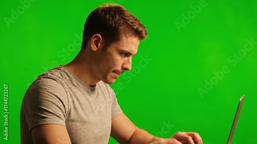 Man Working on Laptop Against Green Screen Background.