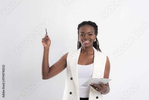 Radiant African American woman with vibrant smile holding tablet and pen embodying inspiration and business acumen studio shot on white background.
