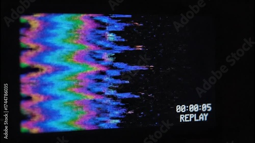 Distorted vintage video display with glitching colorful patterns and replay text flickering