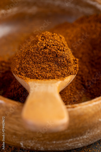 wooden spoon filled with ground spices from dried and ground sweet pepper, aromatic spices from dried red pepper, close up