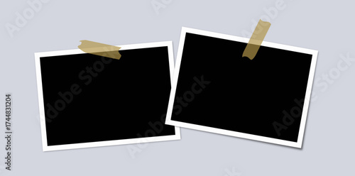 zwei blanko Fotos, die mit Klebestreifen an der Wand befestigt sind