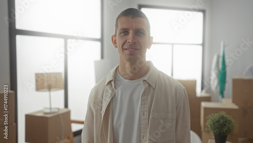 Tableau sur toile Man smiling in new home with moving boxes holding keys in bright living room implying house purchase and relocation