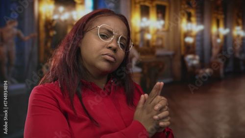 Wallpaper Mural Woman wearing red shirt and glasses makes finger gun gesture in a historic building hall; playfulness. Torontodigital.ca