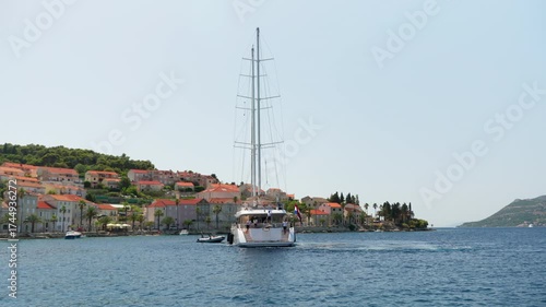 The crew of a large sailing superyacht prepares for stern-to mooring in a harbor. This luxury charter vessel is docking at the quay of a beautiful Adriatic town during a summer vacation in Croatia.