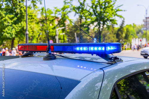 Police vehicle with lights on urban street at sunny summer day
