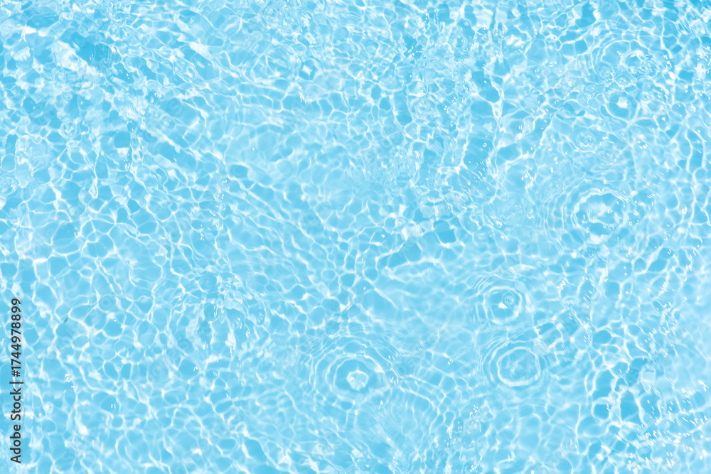 Obraz premium Blue water with ripples on the surface. Defocus blurred transparent blue colored clear calm water surface texture with splashes and bubbles. Water waves with shining pattern texture background.