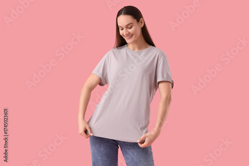 Young woman in grey t-shirt on pink background