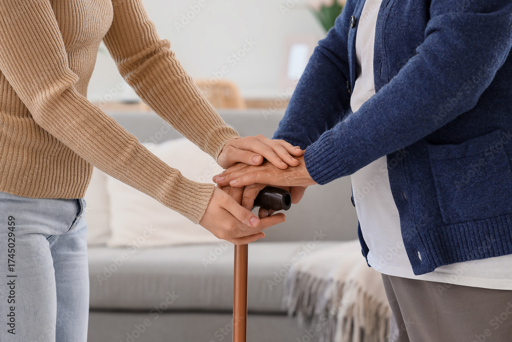 Fototapeta premium Woman and grandmother with stick holding hands at home, closeup. Care concept