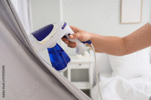 Young woman steaming curtai...
