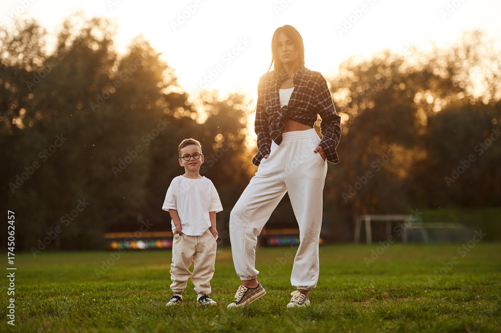 Fototapeta premium Beautiful sunset, standing and posing. Mother and son together in an open field during daytime