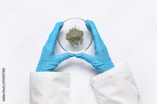 Scientist holding Petri dish with powder on white background