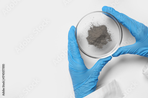 Scientist holding Petri dish with powder on white background