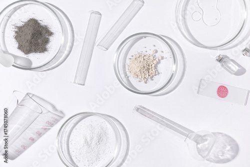 Petri dishes with powder and laboratory equipment on white background