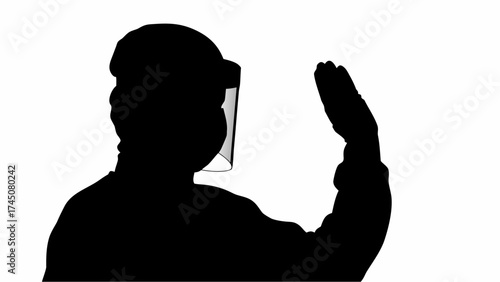Silhouette of person wearing face shield raising hand in greeting or stop gesture, conveying safety and awareness