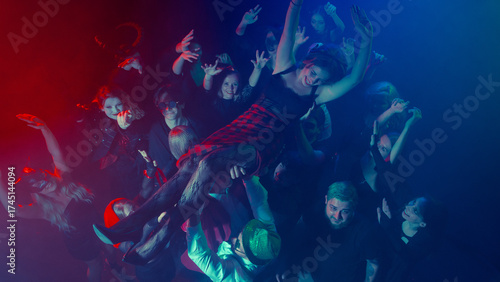 Photography Woman crowd surfing above cheering Halloween party audience