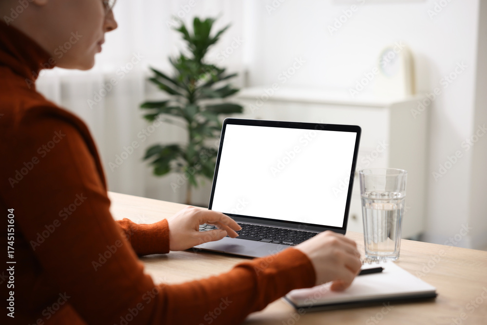 Fototapeta premium Woman working with laptop at wooden table indoors, closeup. Mockup for design