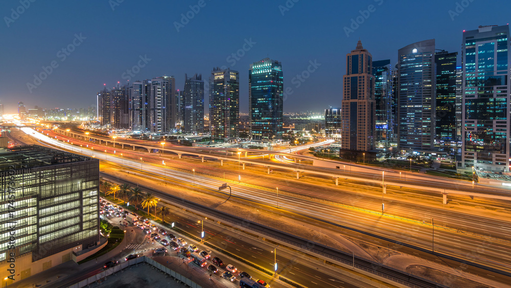 Fototapeta premium Aerial view of Jumeirah lakes towers skyscrapers day to night timelapse with traffic on sheikh zayed road.