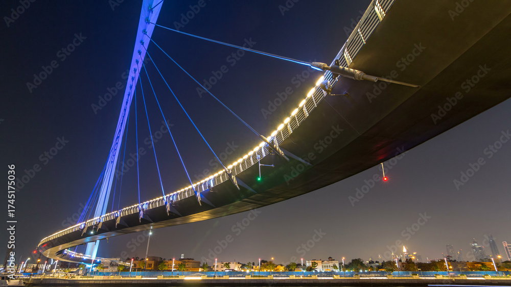 Obraz premium Futuristic Pedestrian Bridge over the Dubai Water Canal Illuminated at Night timelapse hyperlapse, UAE.