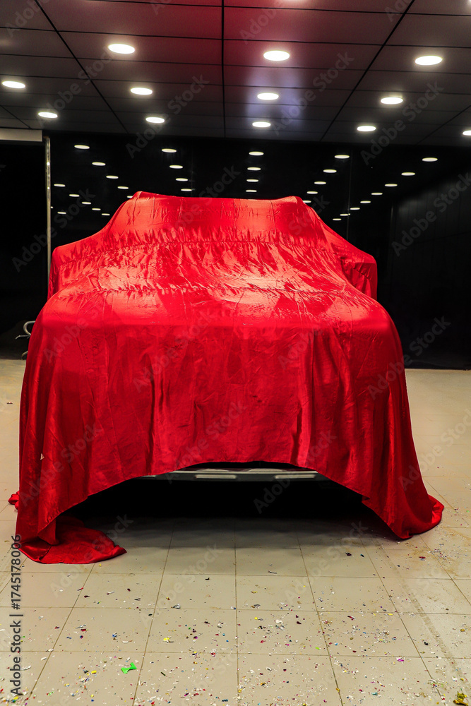 Φωτογραφία Luxury car covered with red cloth in a modern showroom, creating suspense and anticipation for the reveal, capturing elegance, design, and automotive excitement