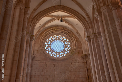 Interior view of the Alcobaca Monastery with a symmetrical rose window and vaulted ceiling in a heritage and solemn space