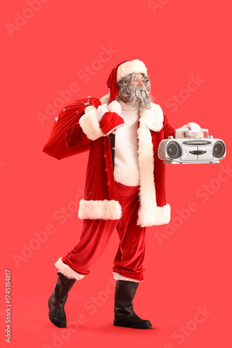 Santa Claus with bag full of gifts and boombox on red background