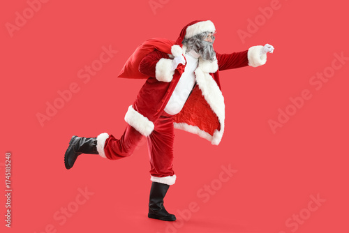 Santa Claus with bag full of gifts running on red background