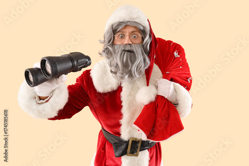 Surprised Santa Claus with bag full of gifts and binoculars on beige background