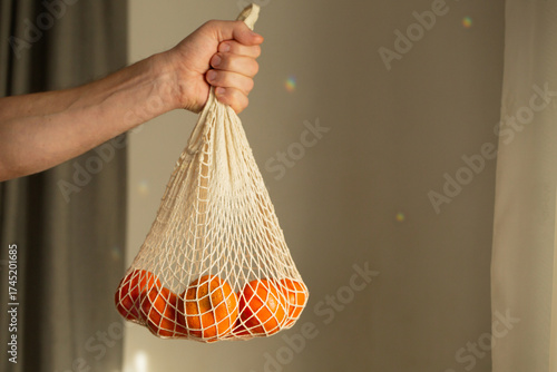 Sustainable lifestyle holding orange filled net bag vertical