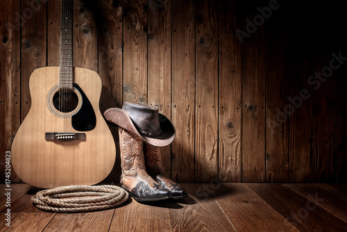 Cowboy hat, boots and acoustic guitar, against blank wooden plank panel grunge background with copy space