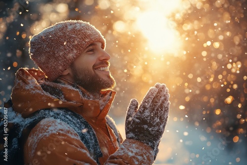 Man in winter clothes smiles, hands up, looking up.