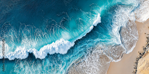 Aerial view of turquoise ocean waves crashing onto sandy beach with rocks