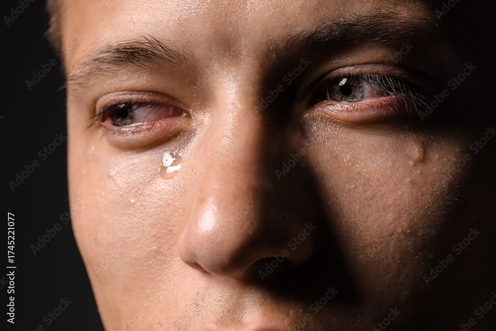Obraz premium Sad man crying on black background, closeup
