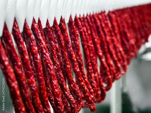 Cured sausage hanging in a food processing facility during daylight hours
