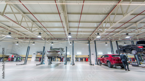 Cars moves on lifts in modern service station and men repair cars timelapse.