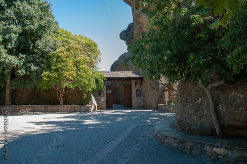 Traditional monastery entrance with wooden door and stone facade and trees around