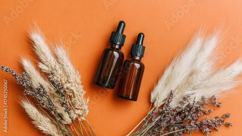 Amber dropper bottles with pampas grass on orange background