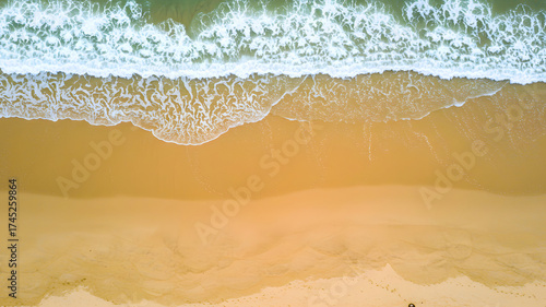 Stunning aerial view of ocean waves meeting golden sand beach