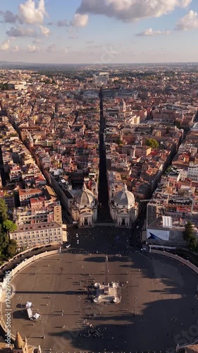 Drone cinematic view of Rome’s Piazza del Popolo with the twin baroque churches Santa Maria in Montesanto and Santa Maria dei Miracoli, iconic film setting and symbol of Roman heritage.