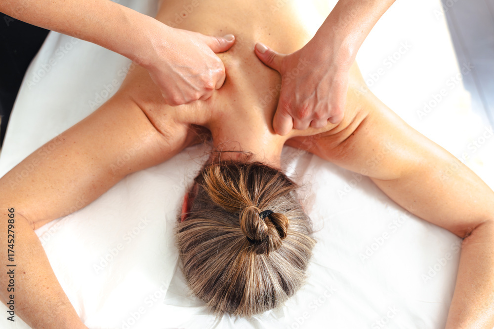 Naklejka premium Close up of therapist massaging back and shoulders of woman in wellness spa, concept of physical therapy, relaxation, body care, pain relief, stress reduction,and professional health treatment session