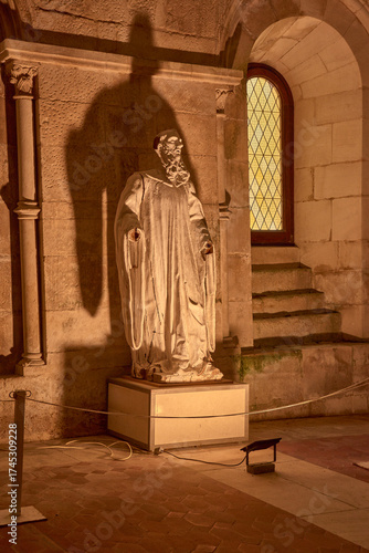 Religious figure in the dining room of the Alcobaca Monastery with warm lighting and a stained-glass window in a spiritual and solemn setting