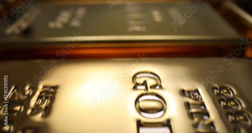 Gold bars lie in row and reflect warm glow across surface. Bullion stack shows weight and serial marks symbolizing wealth and reserve in bank vault